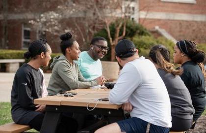 Undergraduate students sitting around a picnic table on the Quad